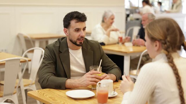 Father and teenage daughter sitting at table in cafe. Light snack or coffee break at restaurant, family getaway or pastime. Family time, Sunday lunch at chain cafe in capitals pedestrian tourist area