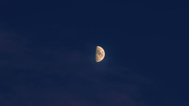 Half moon against dark blue sky at evening, celestial body illuminating night atmosphere, crescent shape moon light against twilight color background, sky scene