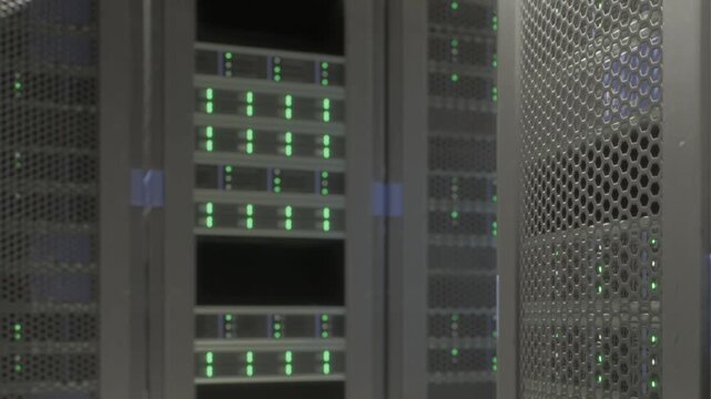 Rows of servers are active and running in a data center during a busy workday. Lights on each server indicate they are processing data. The environment is tech focused and efficient.