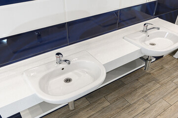 Fototapeta premium dual‑sink bathroom features white ceramic basins with chrome faucets on clean white countertop. blue‑and‑white tiled backsplash wood‑look flooring complete modern look