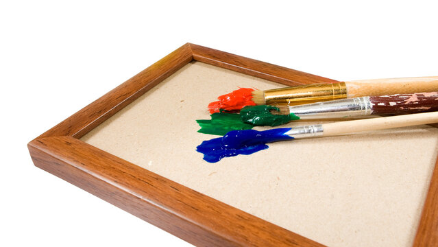 Colorful paint and brushes rest on a wooden frame with a blank canvas ready for artwork