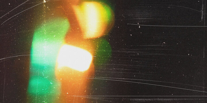 Abstract dark vintage film grain texture with green and orange glowing light leaks