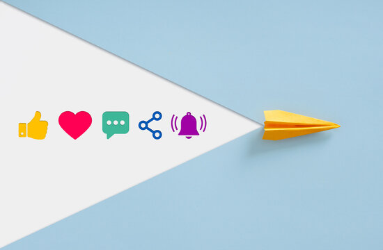 Yellow paper plane sending out social media engagement icons trail.