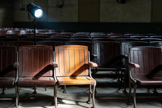 A spotlight falling on one empty chair among many in a dark hall