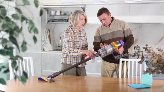 Male salesman tells an elderly woman how to use a new cordless vacuum cleaner . High quality 4k footage