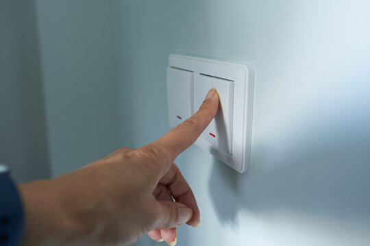 Close-up of a woman's hand turning on a light switch.