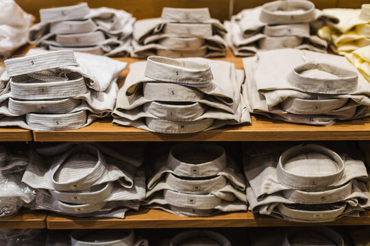 Folded Neutral Shirts Sorted by Size on Wooden Shelves