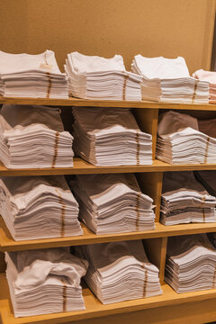 Stacks of White Folded Shirts on Wooden Shelves