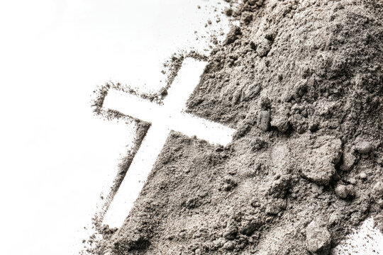 A cross shape appears in the gray ash on a white surface. The scene shows the details of the ash around the cross, creating a stark contrast