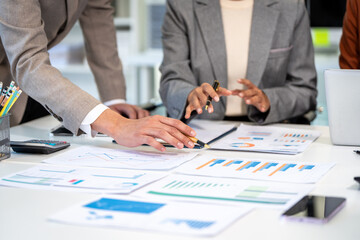 Plakat Business team reviewing financial charts and reports at a desk during a planning meeting, with laptop, calculator, pens and smartphone.