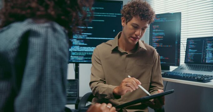 Diverse team developer uses tablet discuss AI coding and project strategy at office. Artificial intelligence software debugging, Cybersecurity database server, Machine learning app meeting concept.