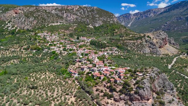 Aerial footage revealing a traditional greek village nestled among mountains and olive tree plantations