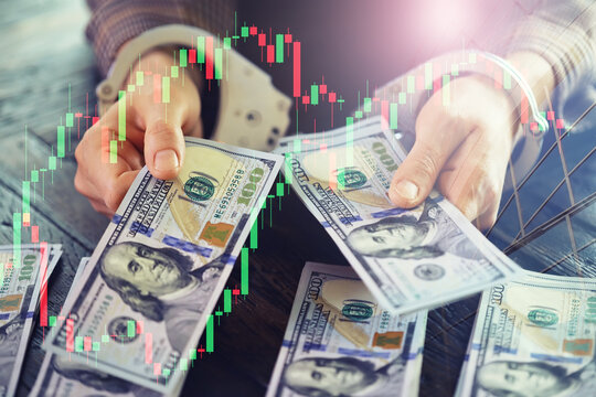 women's handcuffed hands hold dollars. handcuffed hands on a money banknotes background.