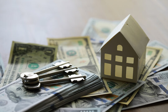 Model of cardboard house with key and dollar bills. Building, loan, real estate, cost of housing or buying a new home concept.