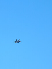 Fototapeta premium Modern Military Stealth Fighter Jet Flying in Clear Blue Sky