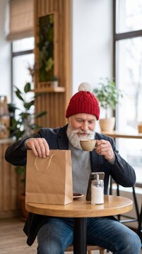 Contemplative senior man sips coffee beside kraft gift bag at cafe table