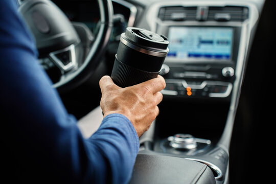Man holding reusable coffee mug inside car