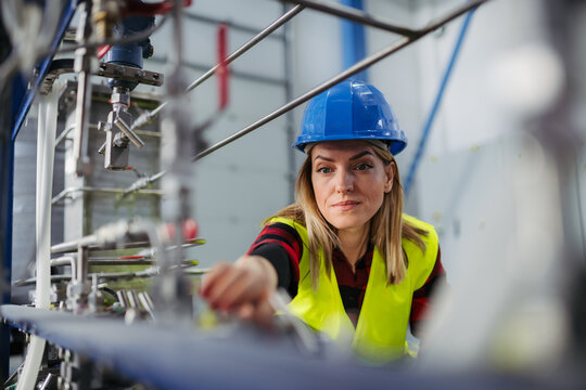 Woman technician checking industrial system during routine maintenance.