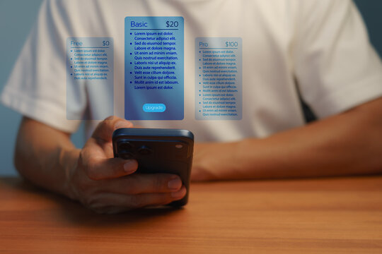 Man holding a smartphone with a futuristic digital hologram showing app subscription pricing plan. Compare basic and premium technology upgrade options for mobile business.