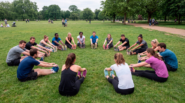 United fitness group stretches together in large circle inside busy city park