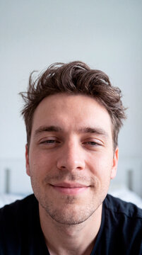Genuine young man gazes calmly at the camera in soft natural window light
