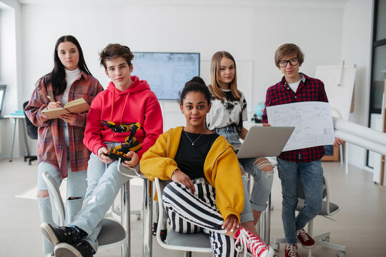 Diverse group of high school students with robotics project in classroom.