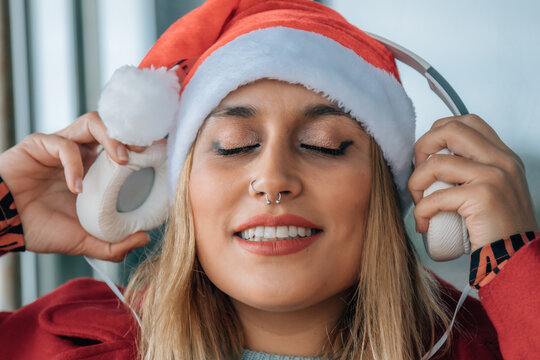 Happy woman with headphones on gray background. Christmas music