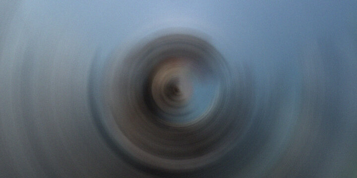 Radial spin blur forming circular hypnotic vortex in muted blue and gray tones suitable for creative minimal designs.