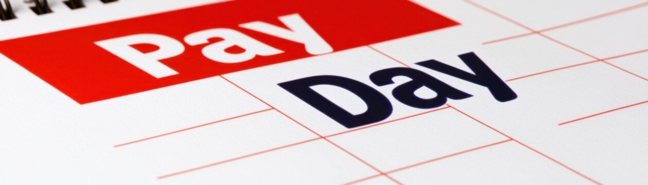 A close-up of a calendar highlighting "Pay Day" in bold letters with red and black text on a white grid background.