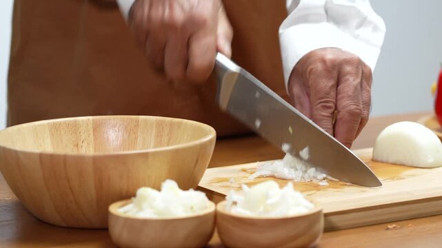 Hand Slicing Onion on Wooden Board in Kitchen.