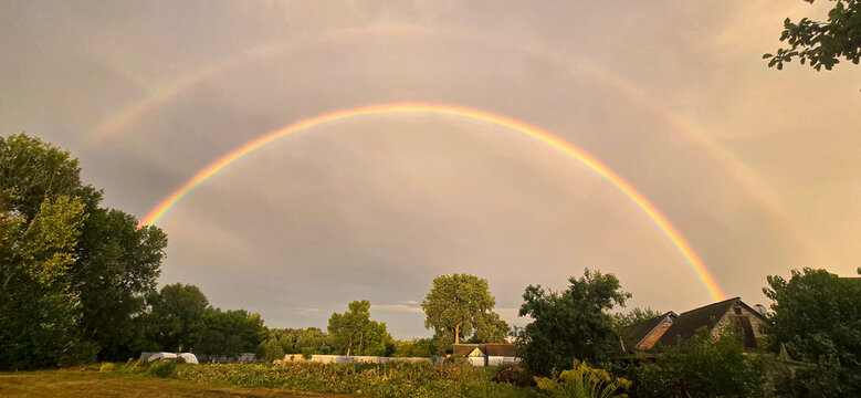 Beautiful double rainbow over a rural village landscape after summer rain