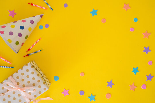 Birthday banner with a party hat, festive candles, and a gift on a yellow background with space for text