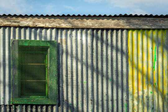 Colourful corrugated iron wall, barn window and blue sky