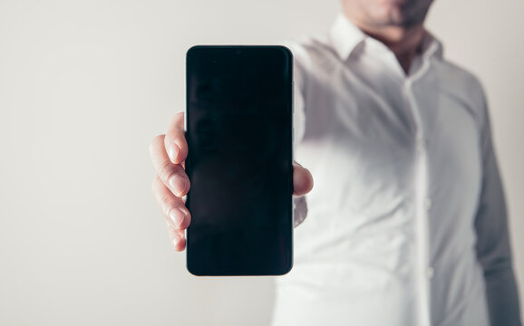 Businessman showing smartphone with blank screen, mock up for your design