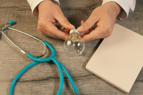 Close-up of a doctor's hands with a stethoscope and a light bulb