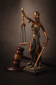 Statue of justice, gavel and scales of justice on dark background