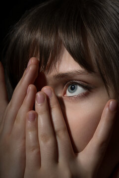 Extreme closeup of a young woman's eye looking through fingers