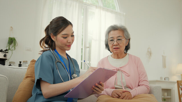 Caregiver nursing home elderly care support in bright home setting, nurse consults elderly woman with calm attentive expression