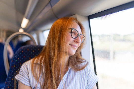 Redhead woman wearing glasses traveling by train