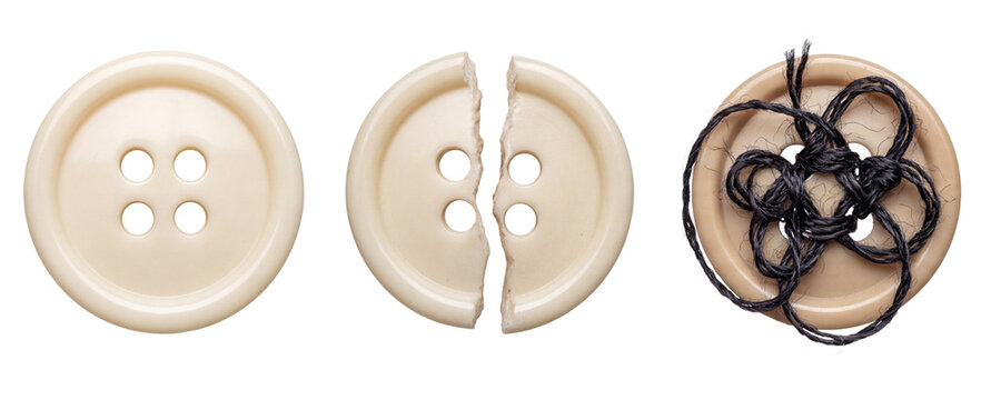Beige plastic buttons, one intact, one broken in half, and one tangled with black thread showing clothing repair, tailoring and sewing concepts