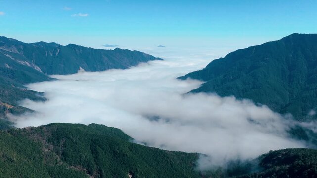 Aerial view of foggy mountain valley with cloud inversion and green fores
