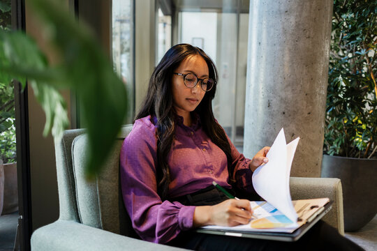 Focused businesswoman reads a document in the office during daytime
