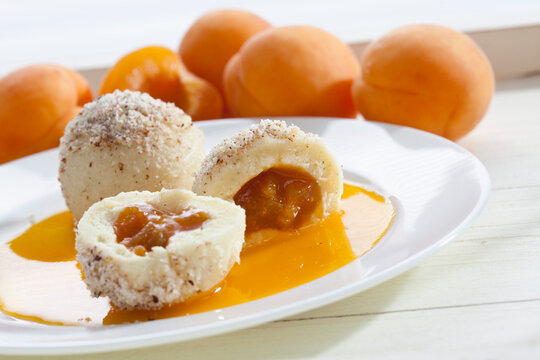 Apricots dumpling with grounded hazelnut on plate and apricots in background