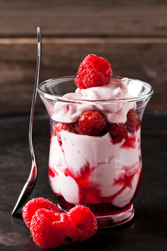 Glass of trifle with whipped cream, strawberries and strawberry sauce
