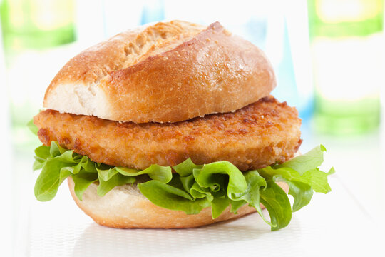 Bread roll with schnitzel on chopping board, close up