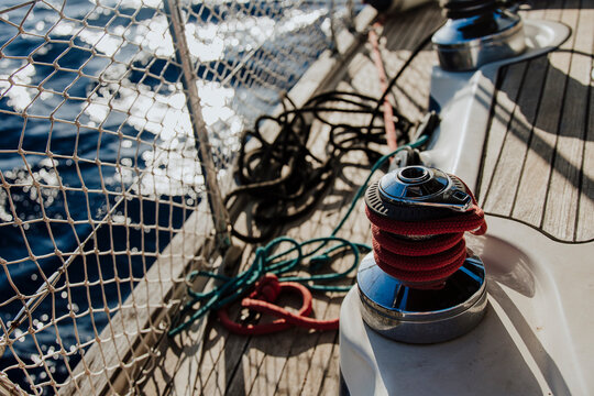 Red rope on a winch on the wooden deck of a sailboat at sea