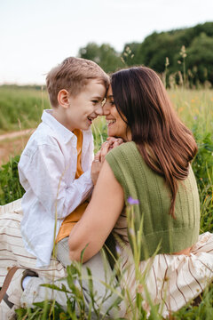 Mother and son touching noses and laughing in a summer field