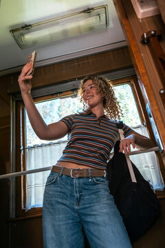 A smiling woman takes a selfie in a train compartment