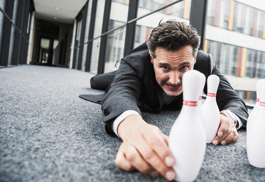 Obsessive manager lying on the floor in office passageway adjusting pins