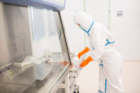 Lab technician wearing cleanroom overall in laboratory for drug production